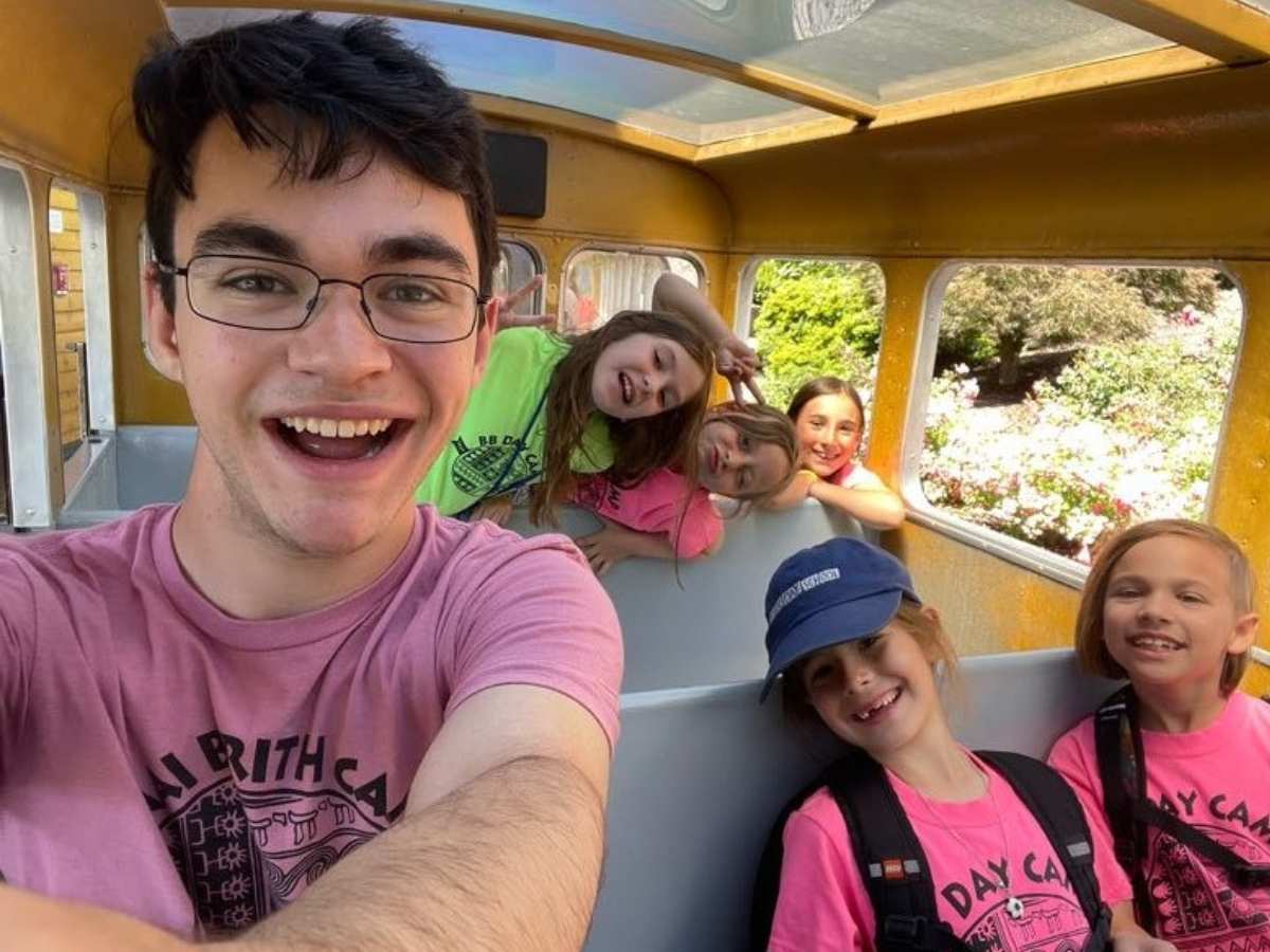 A counselor taking a selfie with campers behind him