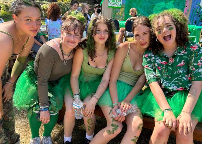 A group of female campers wearing green sitting on a bench