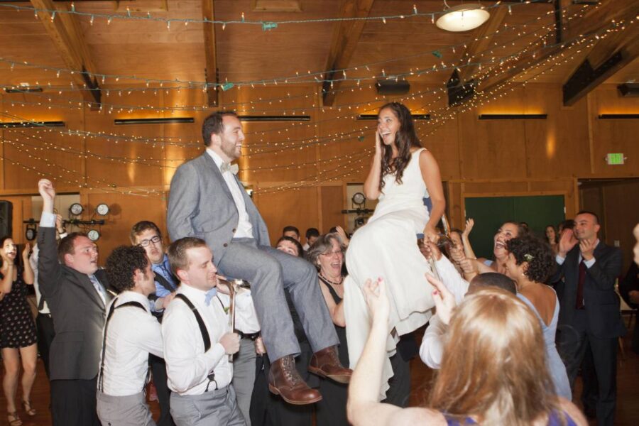 bride and groom being raised on chairs above heads